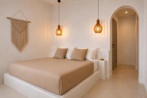 a bed in a white room with two lights at Aegeeis in Perissa