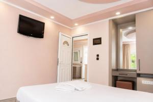 a bedroom with a white bed and a tv on the wall at Hotel Dionysos Polichrono in Polychrono