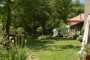a yard with green grass and trees and a house at Pan Demeure et Granges in Montesquieu-Avantès