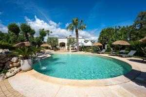 a swimming pool in a yard with chairs and umbrellas at Villa Tonia in Fasano