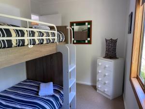 a bedroom with a bunk bed and a dresser at Stewarts Bay Retreat in Port Arthur