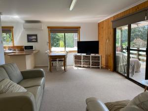 a living room with a couch and a flat screen tv at Stewarts Bay Retreat in Port Arthur