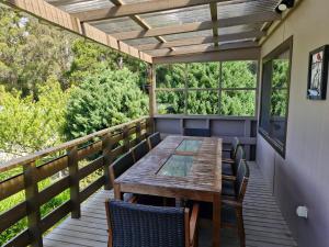 a deck with a wooden table and chairs at Stewarts Bay Retreat in Port Arthur