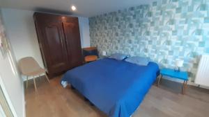 a bedroom with a blue bed and a table and chairs at Entre Golf et Mer RDC in Dieppe