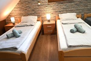 two beds in a room with blue pillows on them at Penzión Kállai a Vináreň in Fiľakovo