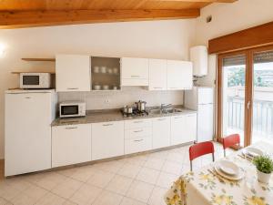 a white kitchen with white cabinets and a table with a tablecloth at Residence Guardamar - Agenzia Cocal in Caorle
