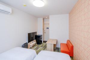 a bedroom with a bed and a table and a chair at たびのホテル佐渡Annex in Sado