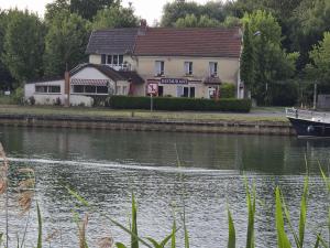 a building next to a river with a boat at Entre 2 Rives in Charly-sur-Marne