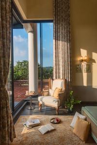 a living room with a chair and a large window at SaffronStays Citadel in Sangolda