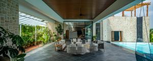 an indoor patio with a pool and tables and chairs at SaffronStays Citadel in Sangolda