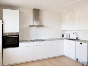 a white kitchen with white cabinets and a sink at Solbacka Apartment in Södra Ås
