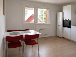 a kitchen with a white table and red chairs at Solbacka Apartment in Södra Ås +7 photos