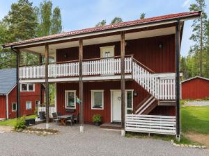 a red house with a large porch and stairs on it at Solbacka Apartment in Södra Ås