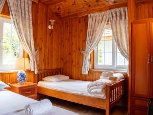 two beds in a room with wooden walls and windows at Atıcı 2 Hotel in Adrasan