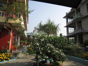 a courtyard of an apartment building with a tree and flowers at New Annapurna Guest House in Pokhara