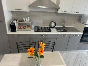 a kitchen with a table with a vase with orange flowers at Portunno Relax House in Fiumicino +10 photos