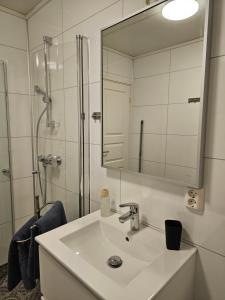a white bathroom with a sink and a mirror at Senja Sjøtun House in Senja
