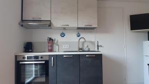 a kitchen with black and white cabinets and a sink at Entre Golf et Mer RDC in Dieppe