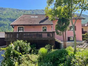 a pink house with a deck in a garden at House Maharac with 3 apartments till 15 persons in Kamno