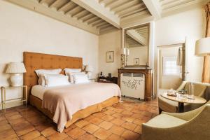 a bedroom with a large bed and a chair at La Maison d'Uzès Relais & Châteaux in Uzès +72 photos