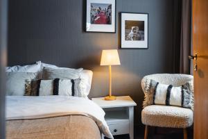 a bedroom with a bed and a chair and a lamp at Bringenatten Hotell Nesbyen in Nesbyen