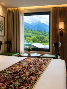 a hotel room with a bed and a large window at The Countryside Resorts Pahalgam in Pahalgām