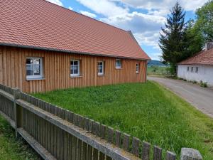 a wooden building with a fence next to a road at Ferienwohnung Landlust in Treuchtlingen