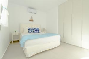 a white bedroom with a bed with a blue pillow at Eidolion Essence - Mykonos Villa with Private Pool in Ano Mera +14 photos