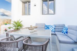 a patio with a white table and chairs and a couch at Eidolion Essence - Mykonos Villa with Private Pool in Ano Mera