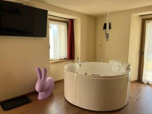 a bathroom with a tub with a pink bunny sitting on the floor at Lo Berio Morgex in Morgex +23 photos