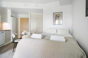 two beds in a white room with a kitchen at Modern Arctic Studio By Lapland Host in Rovaniemi