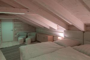 a attic room with two beds and two chairs at Sommarbukt Tind - Luxury Fjord Lodge near Tromsø in Tromsø