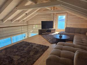 a living room with a couch and a tv at Sommarbukt Tind - Luxury Fjord Lodge near Tromsø in Tromsø