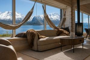 a living room with a couch with a view of mountains at Sommarbukt Tind - Luxury Fjord Lodge near Tromsø in Tromsø +11 photos