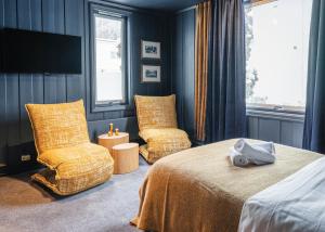 a bedroom with two chairs and a bed and a window at Bringenatten Hotell Nesbyen in Nesbyen