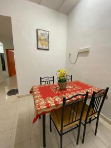 a dining room table with a red table cloth and chairs at Bertam Transit Homestay in Kampong Alor