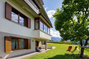 a house with two chairs and a tree at La Veranda - Alpago in Pieve dʼAlpago