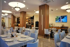 a restaurant with white tables and blue chairs at Lumera Hotel in Durrës
