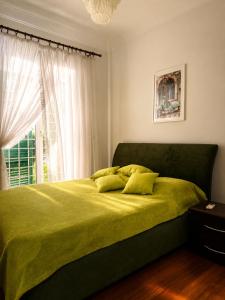 a bedroom with a green bed with a window at Villa SOLE di AMORE - POOL PRIVATE LARGE 100 M 2 - Beach 950m -Center 500 m - ROME & AIRPORT 39 km in Anzio