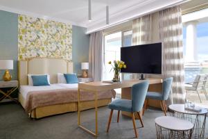 a hotel room with a bed and a desk and a table at Airotel Stratos Vassilikos Hotel in Athens