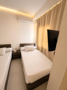 a small room with two beds and a flat screen tv at vila hotel city in Cairo +6 photos