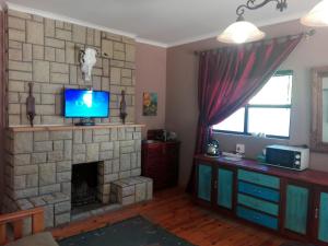 a living room with a fireplace with a tv on top at DeKat Self Catering in Burgersdorp