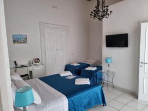 a bedroom with two beds and two blue chairs at Residenza d'epoca Olimpia in Santa Maria di Castellabate