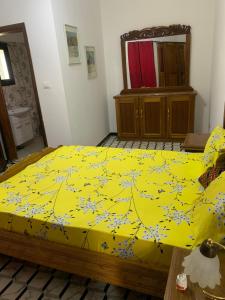 a bedroom with a yellow bed with a yellow comforter at Le Wallo - Residence Sebi in Sébikhoutane