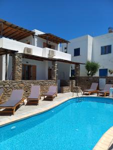 a swimming pool with lounge chairs and a house at Siroco's Rooms And Studios in Parikia