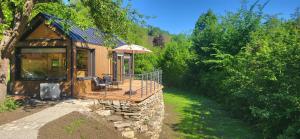 a cabin in the woods with a deck and an umbrella at Tinyhouse am Bach, 3144 Wald in Wald
