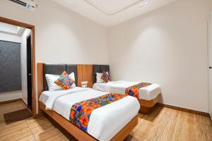 two beds in a room with white walls and wood floors at FabHotel A Square - 400m from Bhimavaram Junction in Bhīmavaram