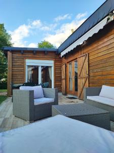 a patio with two wicker chairs and a building at Le Châlet Nature de Lieurey in Lieurey