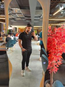 a man taking a picture with his cell phone at اهرمات بورتو السخنه in Madinaty