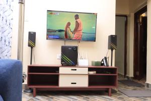a living room with a tv on a wall at BomaZuri Homestays Tala in Nguluni